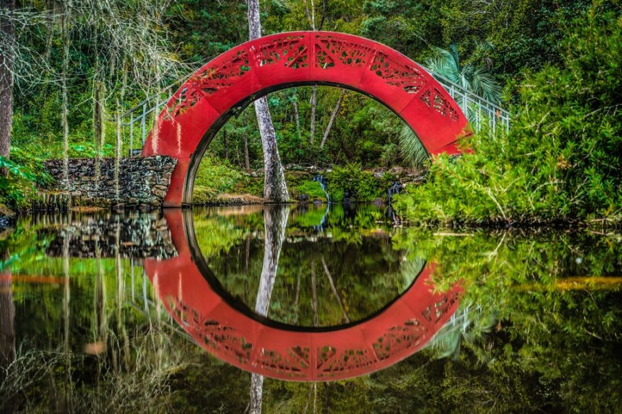 Red Bridge reflecting in water at the Asian American Gardens in Mobile, AL